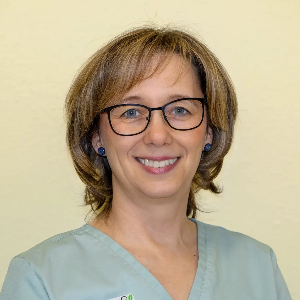 Jana Gerlach, Zahnmedizinische Fachassistentin in der Zahnarztpraxis Eck: Frau mit kinnlangem dunkelblonden Haar und Brille in hellblaugrauem Hemd