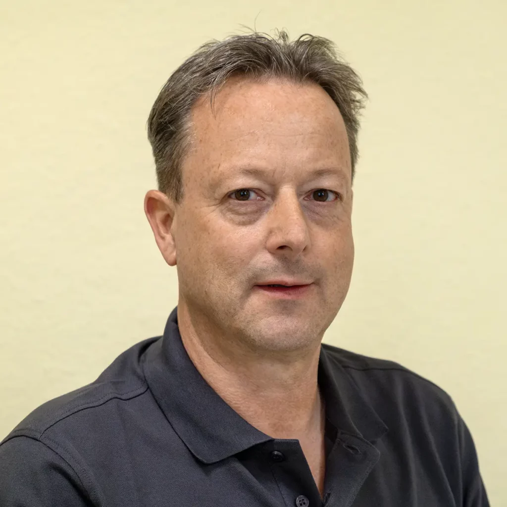 Michael Bresler, Praxismanager der Zahnarztpraxis Eck: Mann mittleren Alters mit grau-braunem Haar und grau-braunem Polohemd